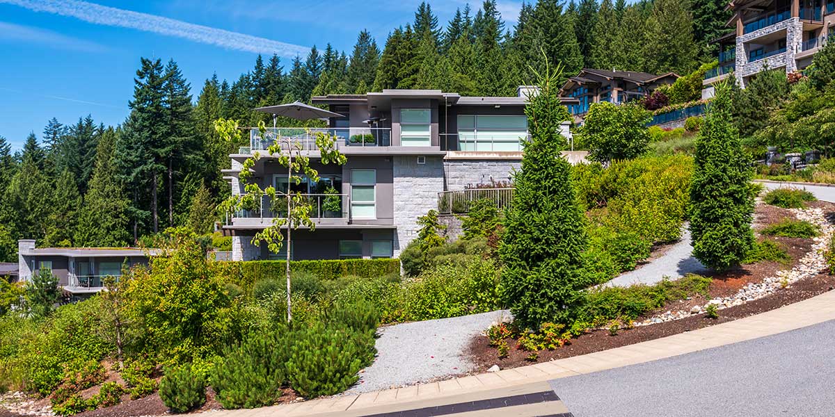Home 2 A multi-story modern custom home built on a steep, lush hillside surrounded by trees, illustrating hillside sloped construction.